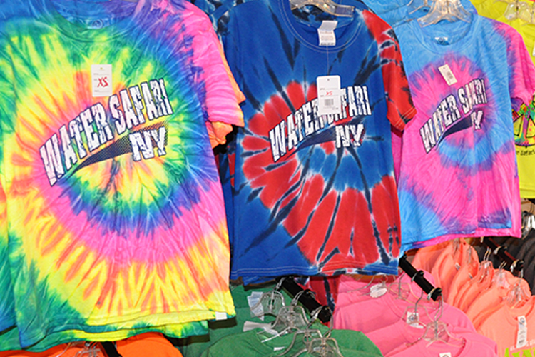 An image of racks of colorful tie-dye t-shirts in the gift shop that read "WATER SAFARI NY".